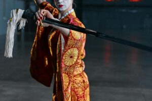 A woman in an ornate kimono brandishing a katana, exuding elegance and strength.